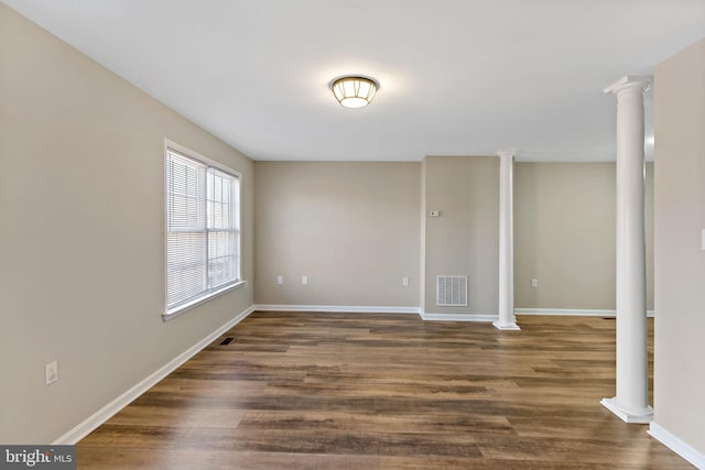 unfurnished room with visible vents, dark wood-type flooring, baseboards, and decorative columns