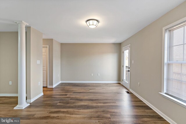 interior space featuring decorative columns, plenty of natural light, baseboards, and dark wood finished floors