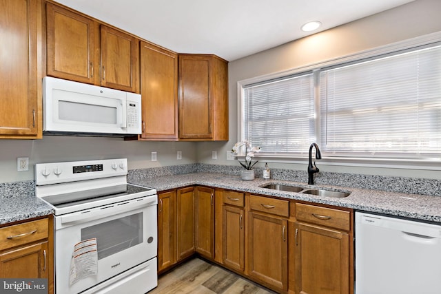 kitchen featuring a sink, white appliances, and brown cabinetry