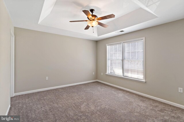 empty room featuring visible vents, a raised ceiling, carpet, and baseboards