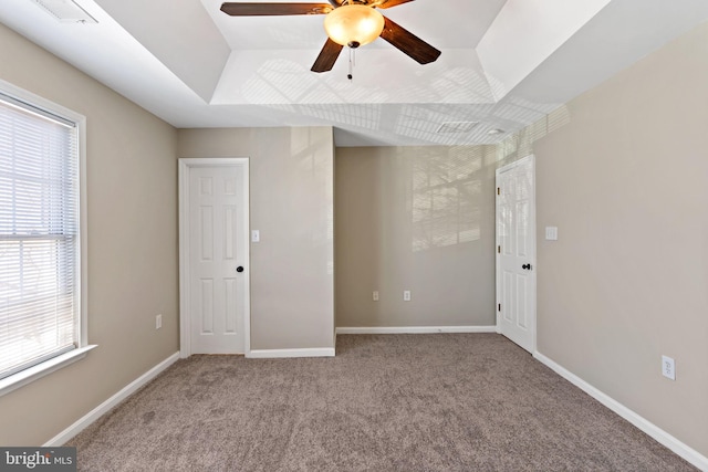 empty room featuring a raised ceiling, baseboards, visible vents, and carpet floors