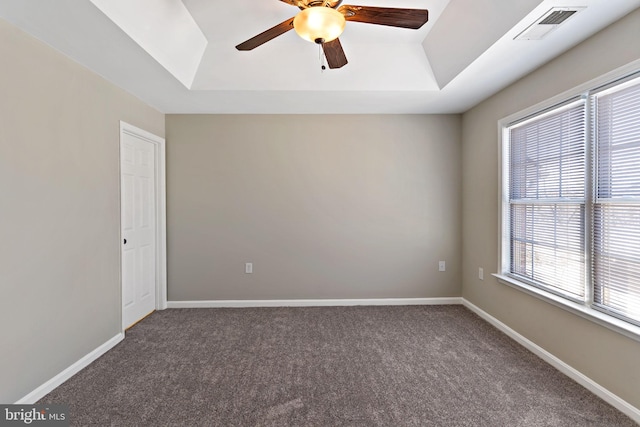 spare room with visible vents, a raised ceiling, carpet, and baseboards