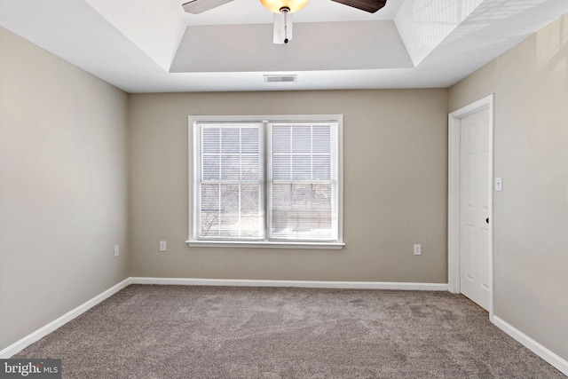 unfurnished room with a tray ceiling, carpet flooring, baseboards, and visible vents