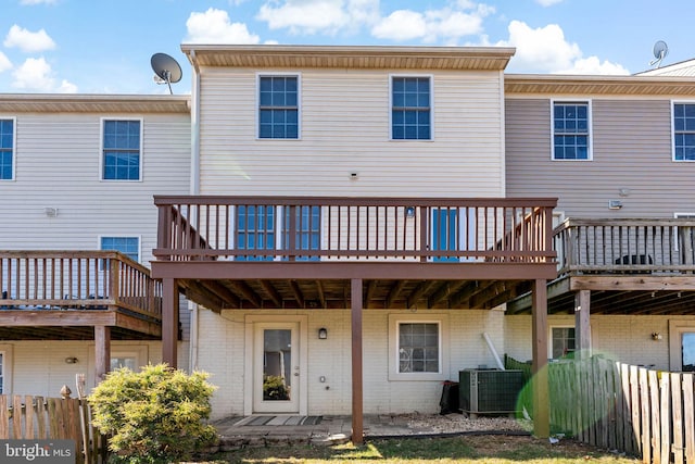 back of property with cooling unit, brick siding, and a wooden deck