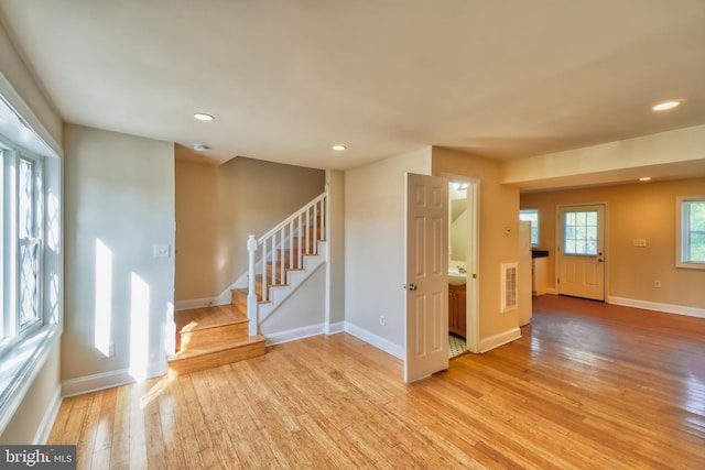 empty room featuring visible vents, baseboards, stairs, recessed lighting, and light wood-style floors