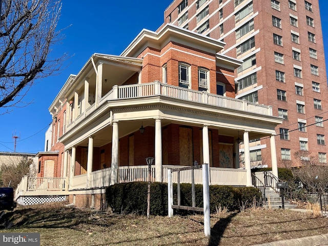 view of property exterior with a porch, a balcony, and brick siding