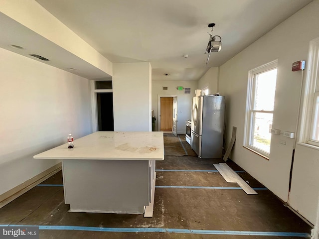 kitchen featuring light countertops, baseboards, freestanding refrigerator, and a center island