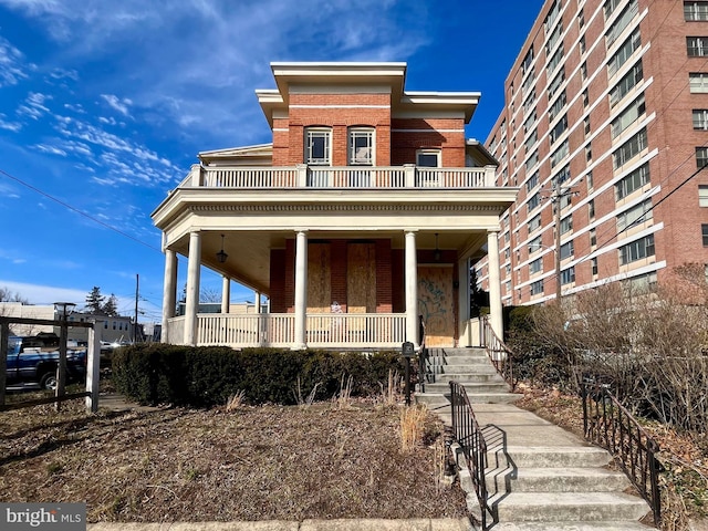 view of front facade with brick siding, a porch, and a balcony