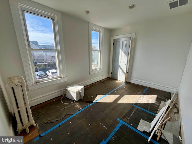 foyer featuring visible vents, a healthy amount of sunlight, an AC wall unit, and baseboards