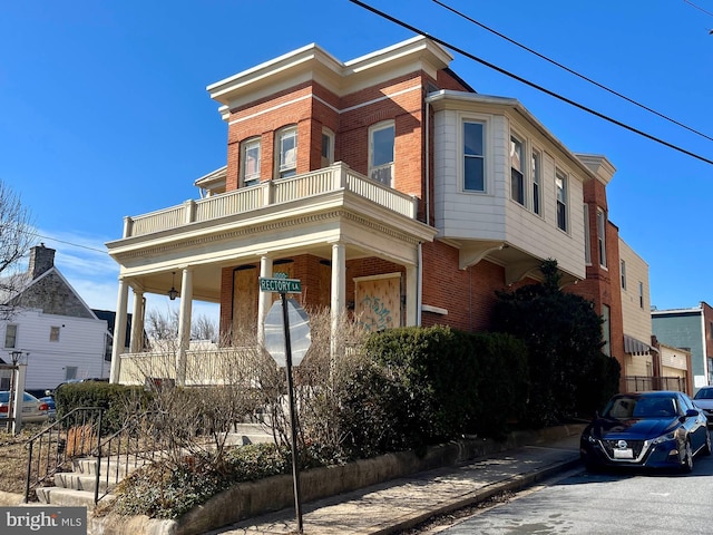 view of property with brick siding and a balcony