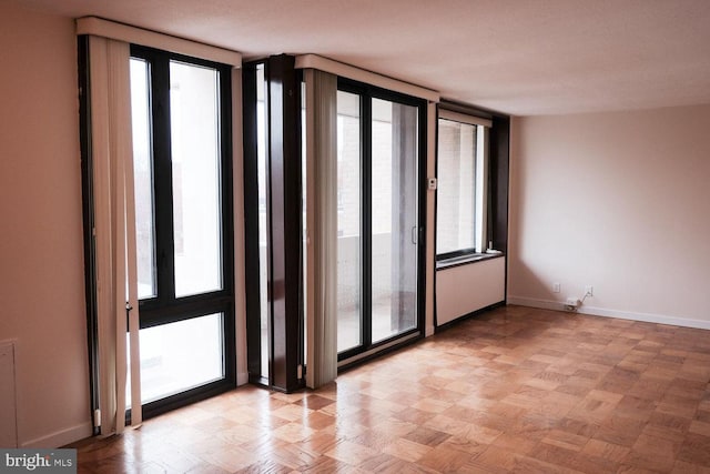 spare room with floor to ceiling windows, a healthy amount of sunlight, and baseboards