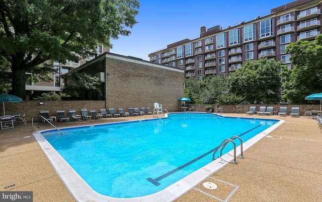 community pool with a patio and fence