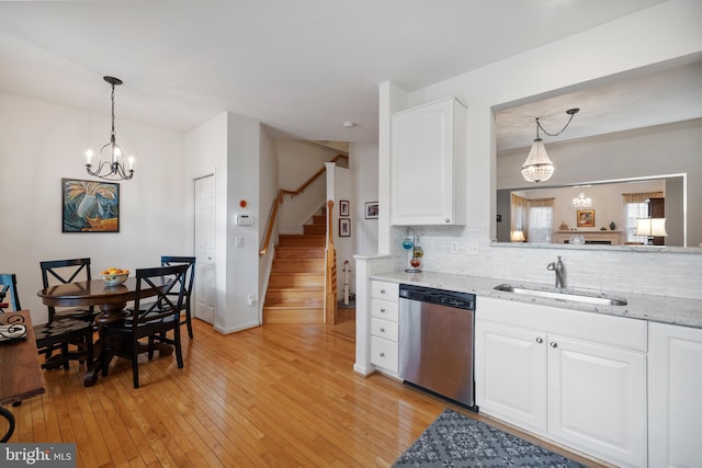 kitchen featuring backsplash, dishwasher, light wood-type flooring, white cabinets, and a sink