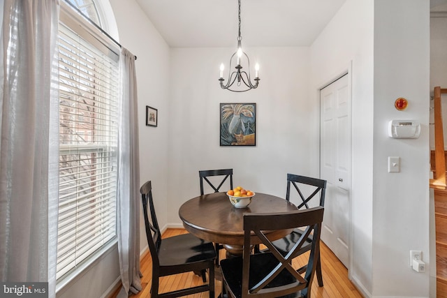 dining room with baseboards, an inviting chandelier, and light wood finished floors