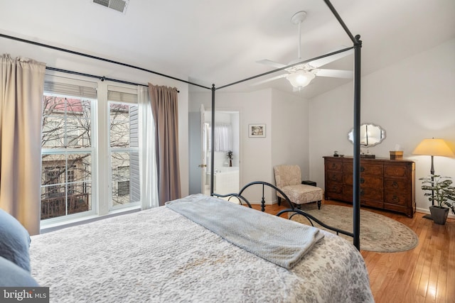 bedroom featuring visible vents, a ceiling fan, wood finished floors, baseboards, and lofted ceiling