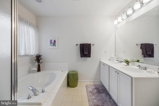 bathroom with baseboards, double vanity, a sink, tile patterned floors, and a bath