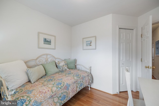 bedroom with light wood-style floors, a closet, and baseboards