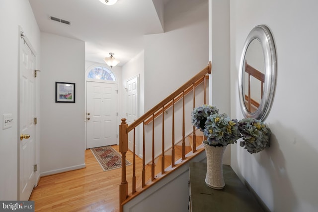 entryway with visible vents, baseboards, light wood-style floors, and stairway