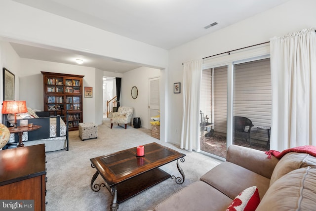 living area featuring stairway, visible vents, and carpet floors