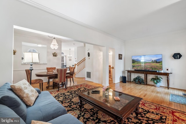 living room with wood finished floors, a notable chandelier, and ornamental molding