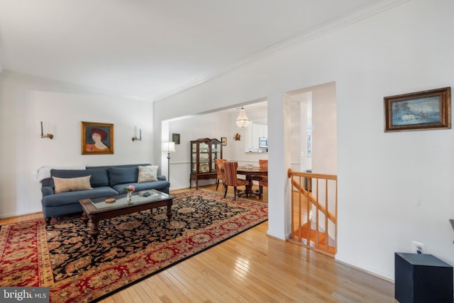 living room featuring baseboards, light wood-style floors, and ornamental molding