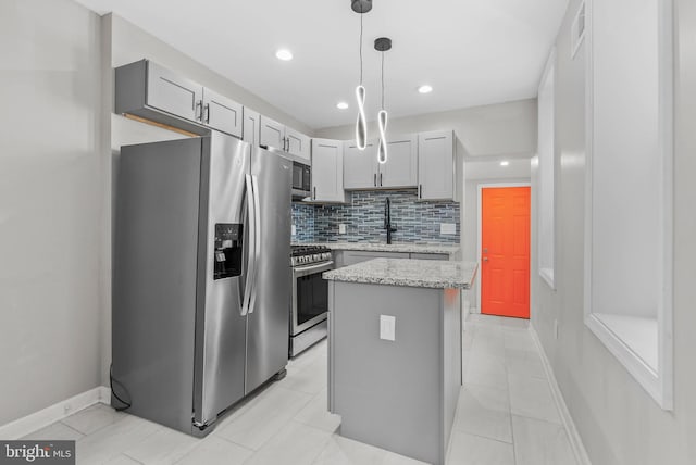 kitchen with a sink, tasteful backsplash, a kitchen island, appliances with stainless steel finishes, and light stone countertops