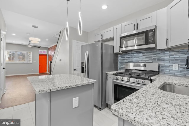 kitchen with a ceiling fan, tasteful backsplash, appliances with stainless steel finishes, and a center island