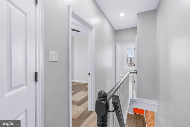 corridor with wood finished floors, an upstairs landing, and baseboards