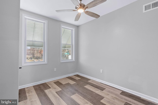 spare room featuring visible vents, a ceiling fan, baseboards, and wood finished floors