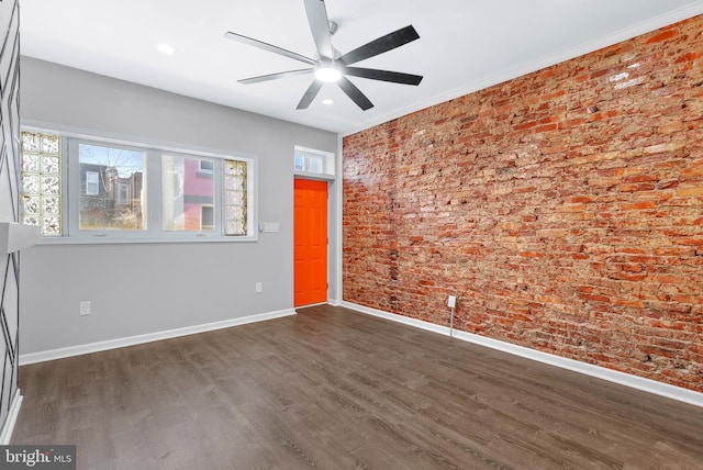 spare room with baseboards, plenty of natural light, dark wood finished floors, and brick wall