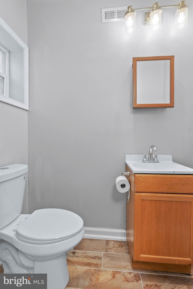 half bath with toilet, vanity, and baseboards