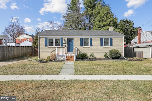 view of front of house featuring brick siding, a chimney, a front lawn, and fence