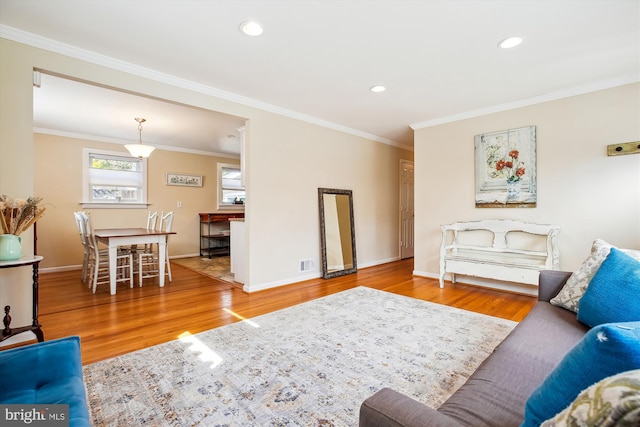 living room with crown molding, baseboards, and wood finished floors