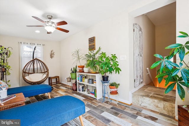 living area featuring wood finished floors, baseboards, and ceiling fan