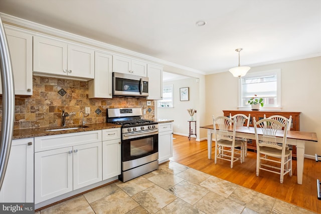 kitchen featuring a sink, dark stone counters, appliances with stainless steel finishes, white cabinets, and decorative backsplash