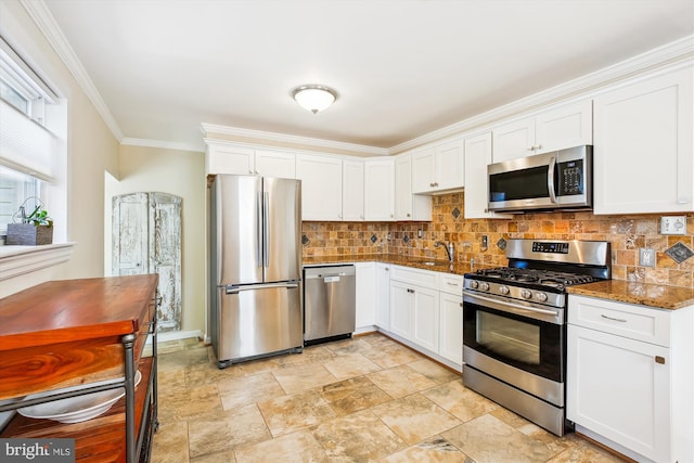 kitchen featuring ornamental molding, decorative backsplash, white cabinets, stainless steel appliances, and a sink