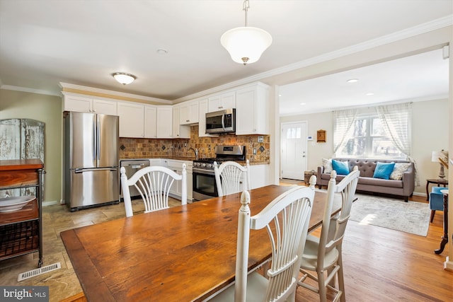 dining room with visible vents, crown molding, baseboards, recessed lighting, and light wood-style flooring