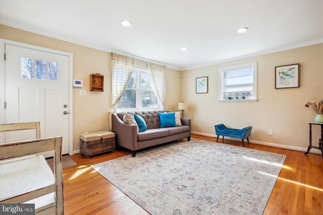 living area with baseboards, ornamental molding, and light wood finished floors