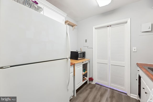 kitchen with wood finished floors, freestanding refrigerator, butcher block countertops, white cabinets, and stainless steel microwave