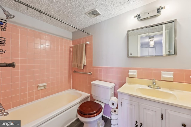 full bathroom featuring vanity, visible vents, a textured ceiling, tile walls, and toilet