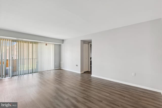 unfurnished room featuring dark wood finished floors, visible vents, and baseboards