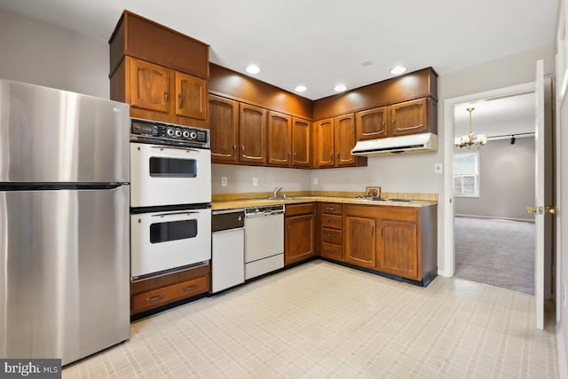 kitchen featuring light countertops, recessed lighting, an inviting chandelier, exhaust hood, and white appliances