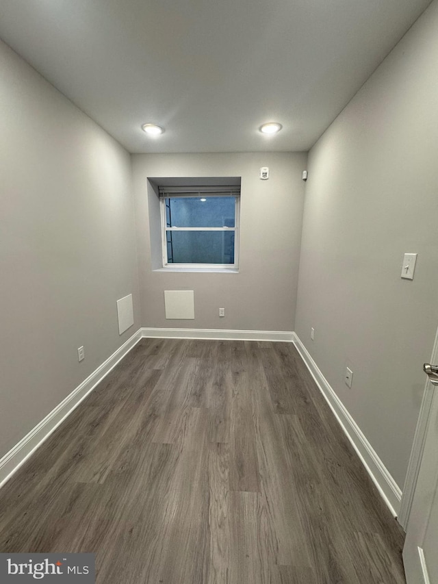 spare room featuring baseboards and dark wood-style flooring