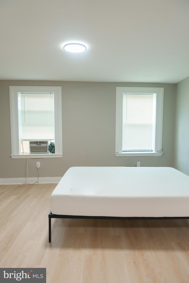 bedroom featuring cooling unit, baseboards, and light wood-style flooring