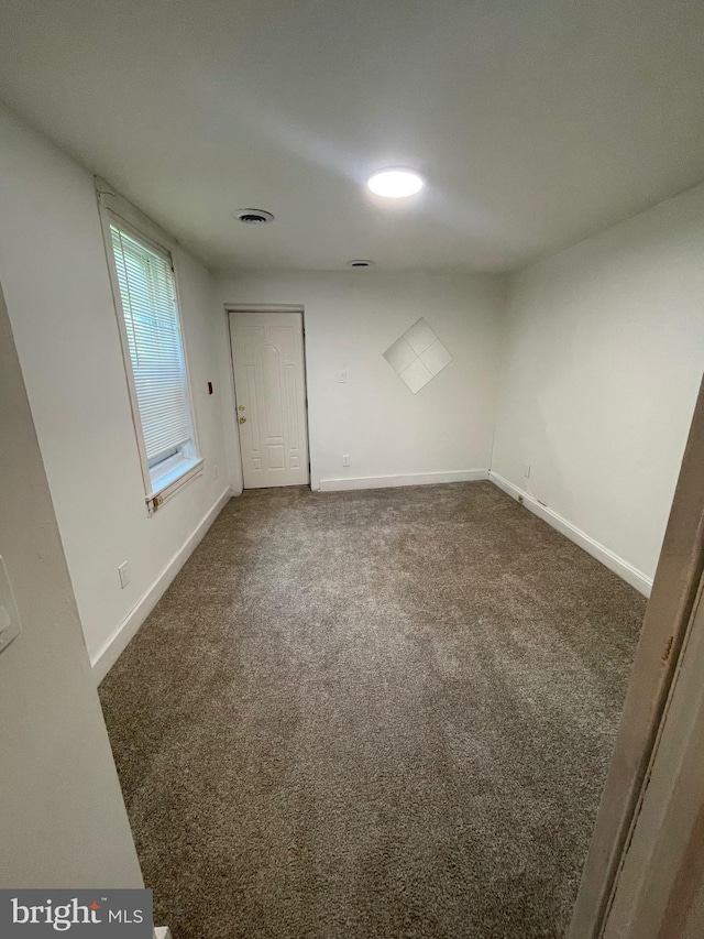 carpeted spare room featuring baseboards and visible vents