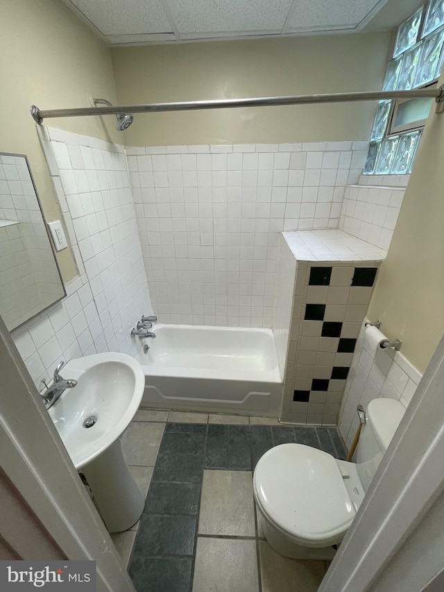 bathroom featuring a sink, a paneled ceiling, shower / tub combination, toilet, and tile walls