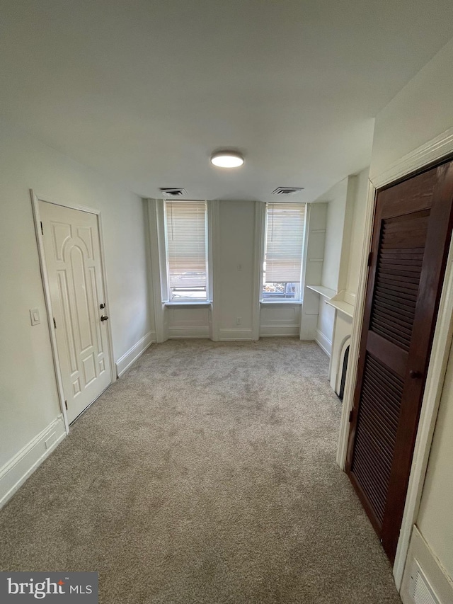 unfurnished bedroom with baseboards, light carpet, and visible vents