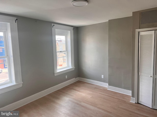 unfurnished bedroom featuring a closet, light wood-type flooring, and baseboards