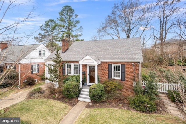 view of front of property with fence, brick siding, roof with shingles, and a chimney