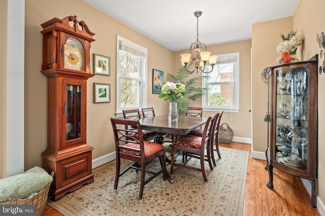 dining room with a notable chandelier, light wood-type flooring, and baseboards